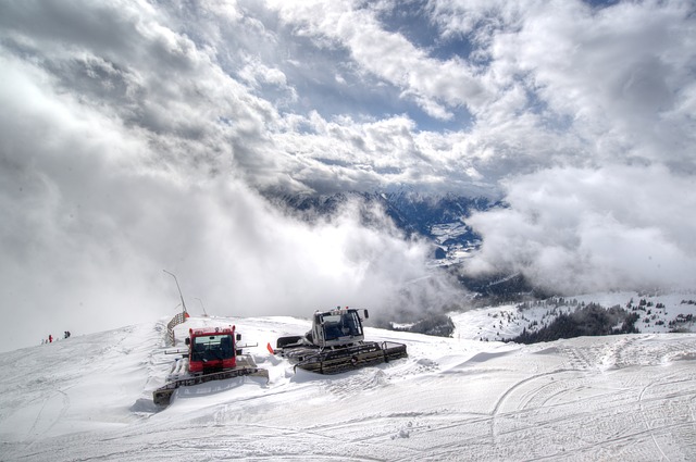 Snow grooming machines, hard at work on the side of a mountain. 